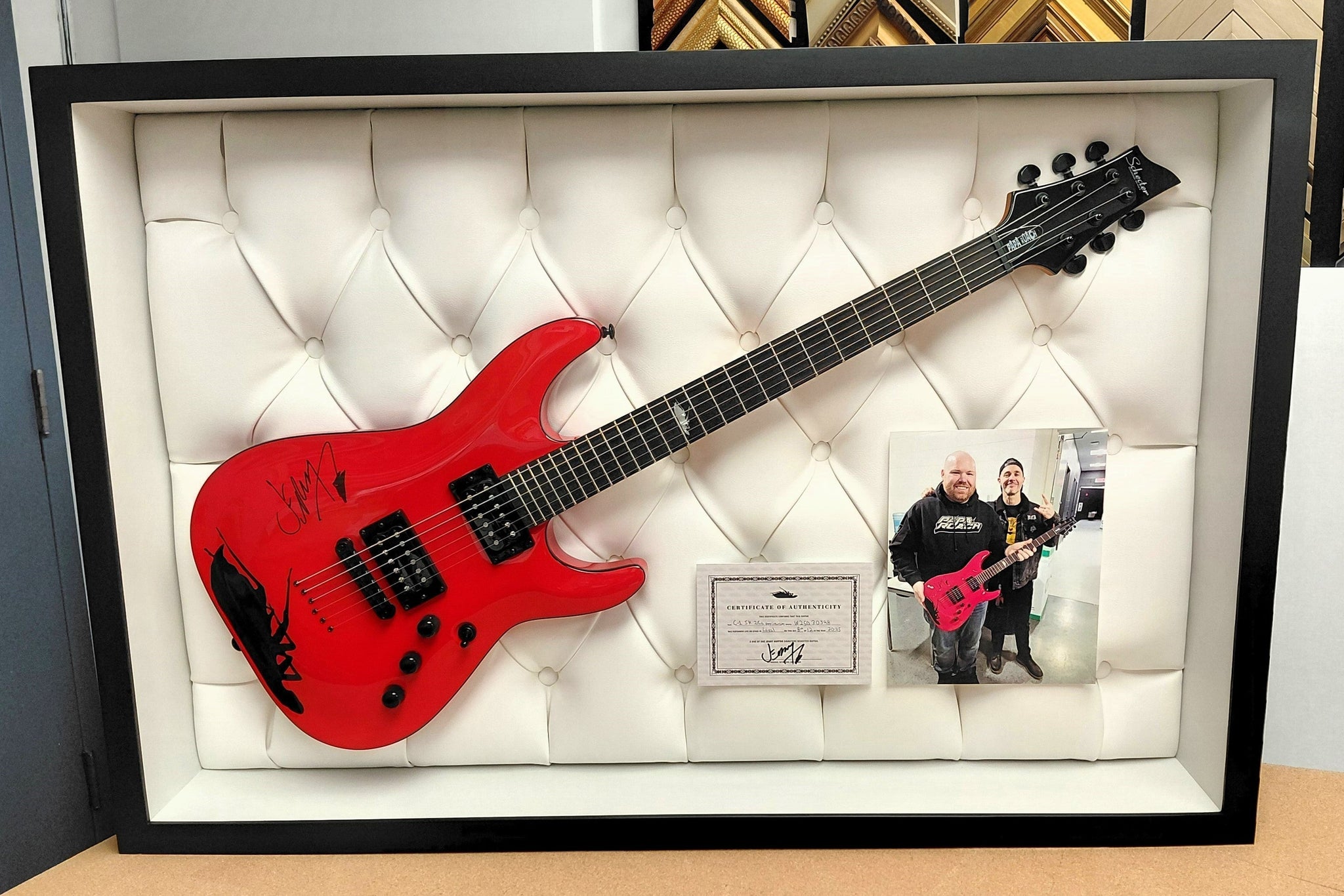 Autographed red electric guitar displayed in a 6-inch deep seamless shadowbox with custom upholstered backing
